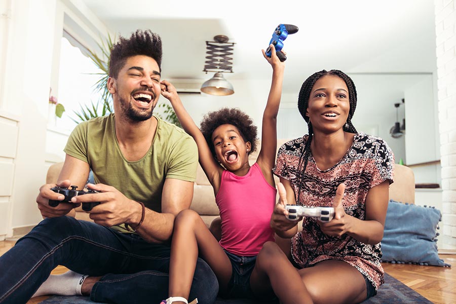 Personal Insurance - Mother and Father Playing Video Games with Their Young Daughter between Them Playing and Cheering